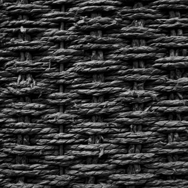 Tight diamond weave of dark woven rattan, grayscale texture