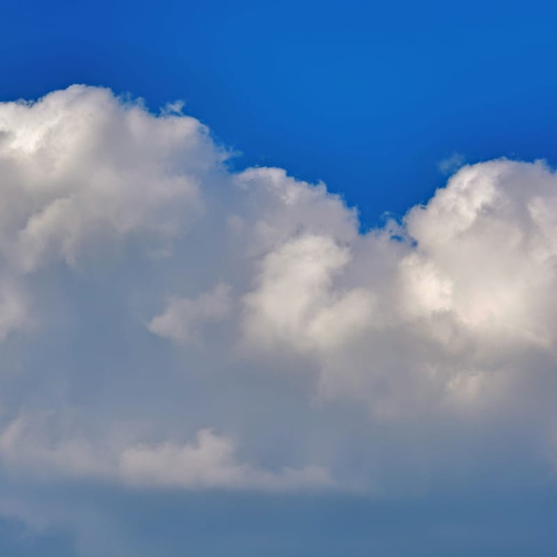 Billowing white cumulus clouds against a deep blue sky