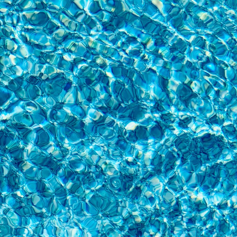 Turquoise pool water rippling in a cellular light pattern, sunlit and abstract